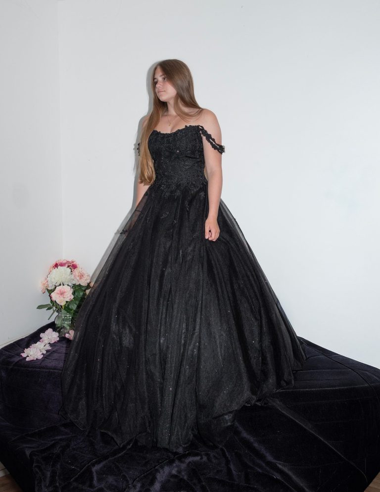 A model in a black off-shoulder ball gown stands against a white background.