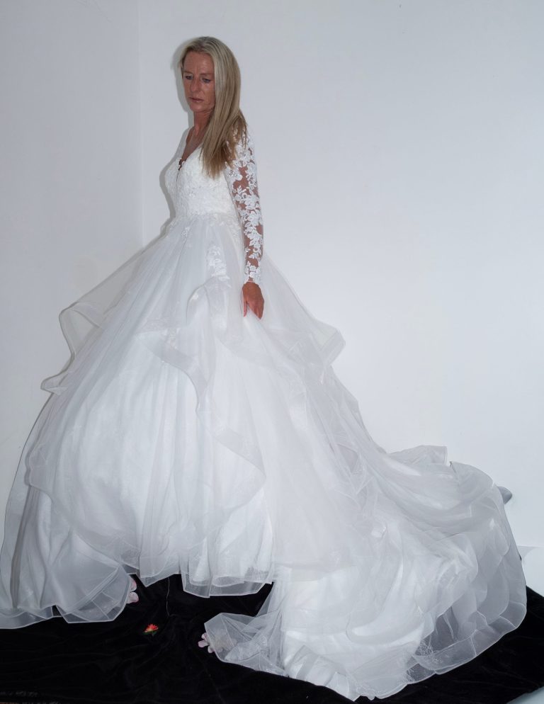 A woman in a flowing white wedding dress with long lace sleeves.