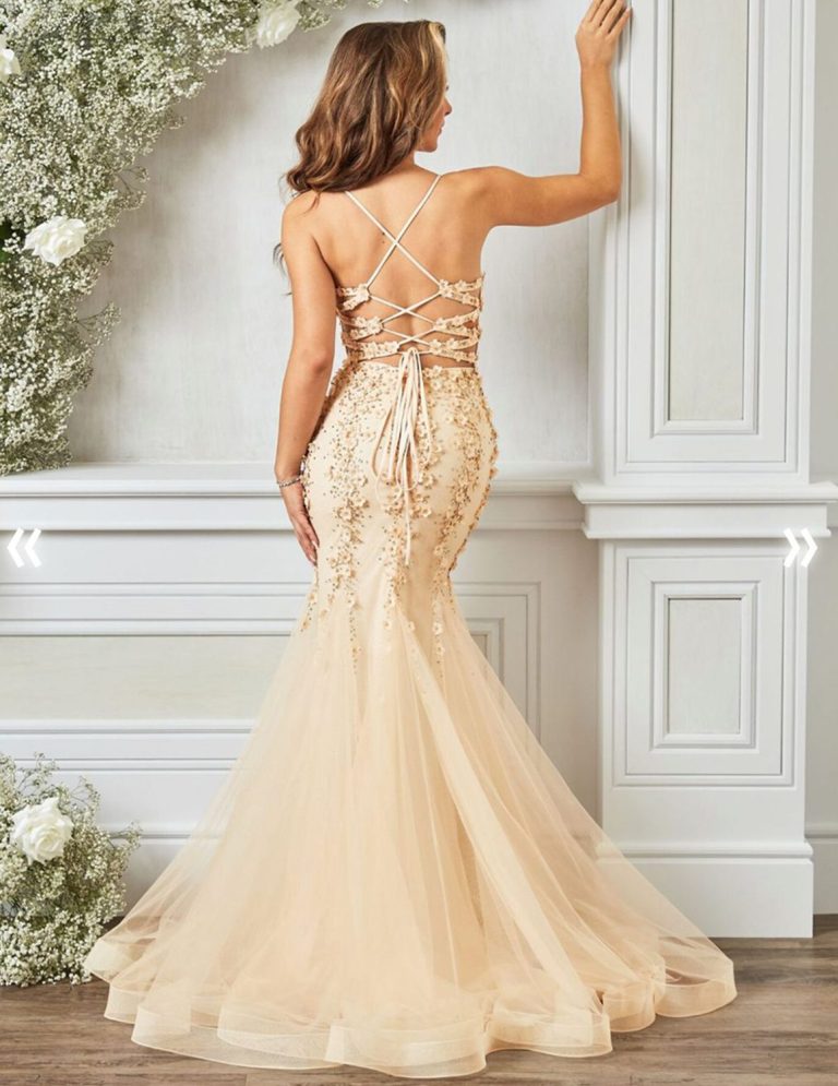 A woman in a fitted, peach mermaid gown with a lace back and flowing train.