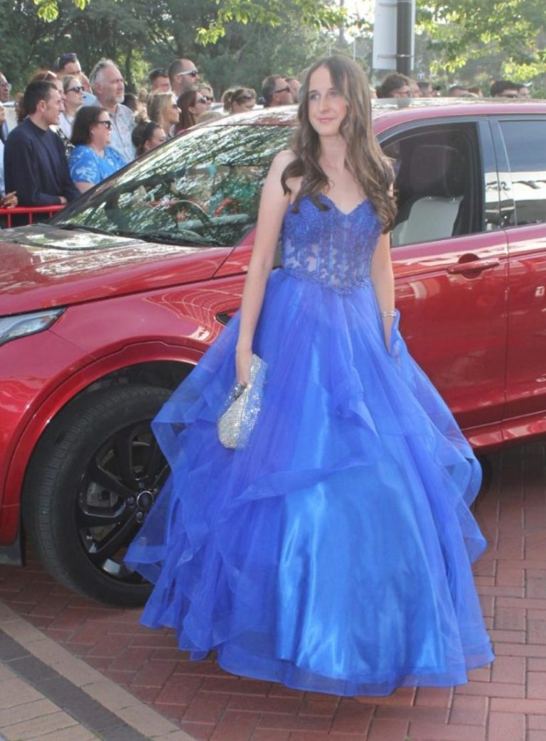 Three elegant dresses in various colours displayed next to a plush chair.